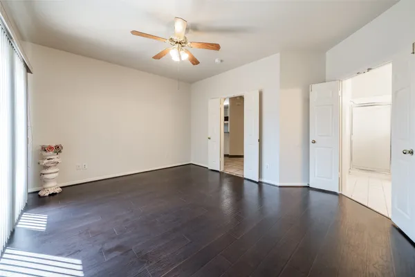 an empty room with wooden floor a ceiling fan and windows