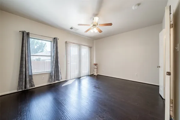 an empty room with wooden floor fan and windows