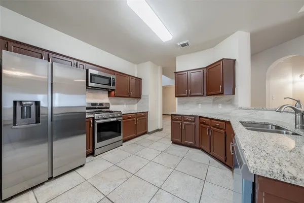 a kitchen with stainless steel appliances granite countertop a sink stove and refrigerator