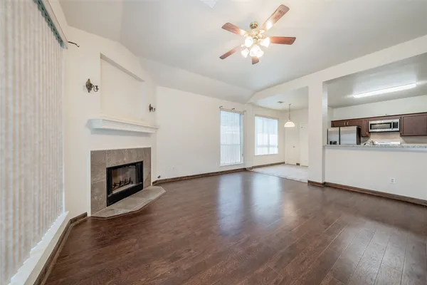 a view of a livingroom with a fireplace a ceiling fan and windows