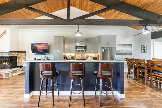 a kitchen with stainless steel appliances kitchen island granite countertop a dining table chairs and a stove