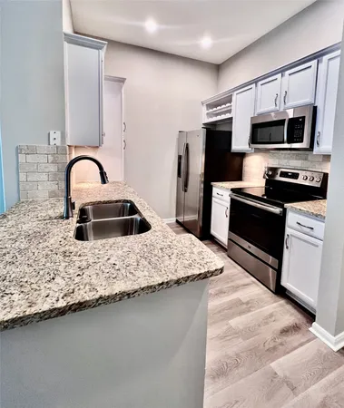 a kitchen with stainless steel appliances granite countertop a sink a stove top oven and refrigerator