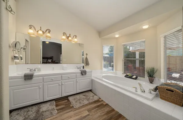 a spacious bathroom with a double vanity sink a large mirror and bathtub