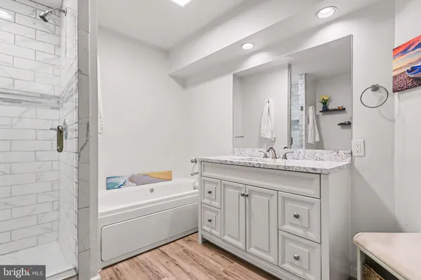 a bathroom with a granite countertop sink a mirror and a bathtub