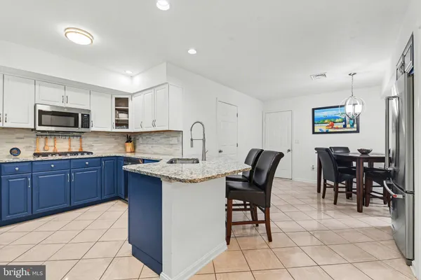 a kitchen with stainless steel appliances granite countertop a table chairs sink and microwave