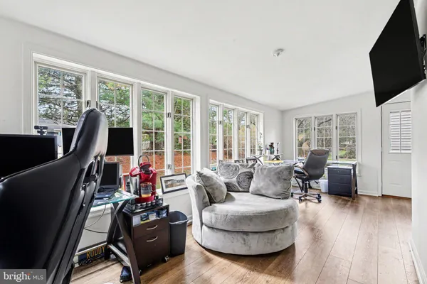 a living room with furniture floor to ceiling window hardwood floor and a flat screen tv