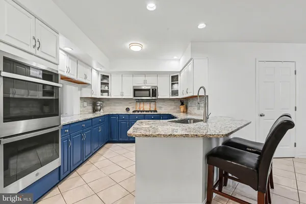 a kitchen with stainless steel appliances granite countertop a stove a sink a microwave a refrigerator and cabinets