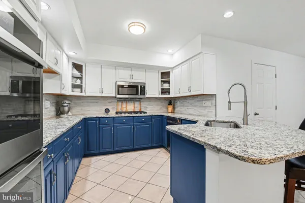 a kitchen with stainless steel appliances granite countertop a sink dishwasher stove refrigerator and microwave with wooden cabinets