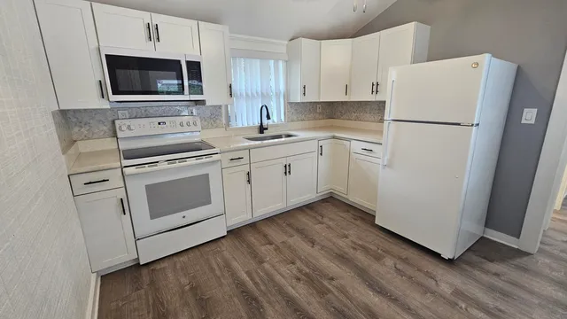 a kitchen with cabinets stainless steel appliances and wooden floor