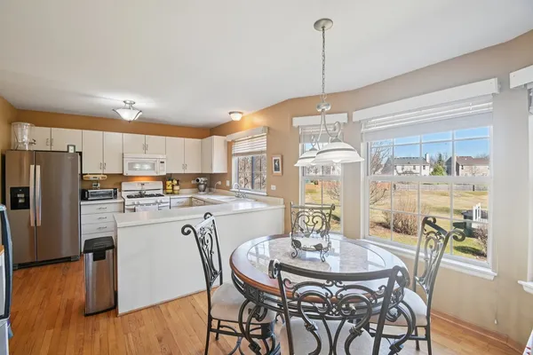 a kitchen with stainless steel appliances granite countertop a dining table chairs and white cabinets