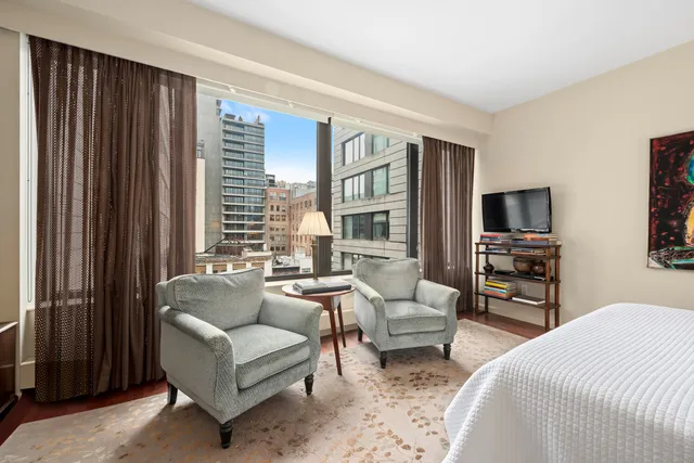 a living room with furniture a flat screen tv and floor to ceiling window