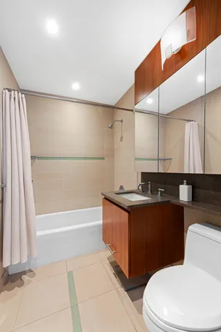 a bathroom with a granite countertop sink a toilet a mirror and bathtub