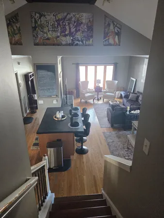 a living room with couches and kitchen view with wooden floor