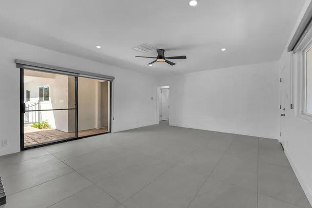an empty room with window and ceiling fan