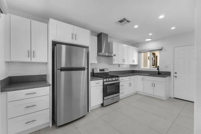 a kitchen with granite countertop white cabinets and stainless steel appliances
