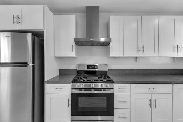 a kitchen with granite countertop white cabinets and stainless steel appliances