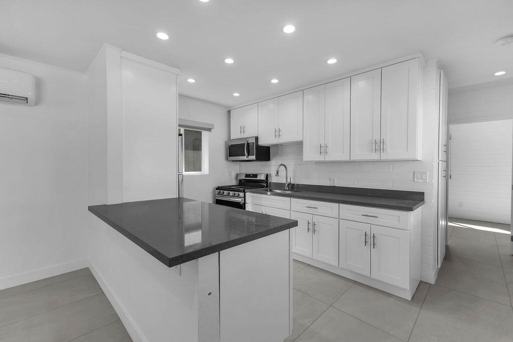 44635 San Carlos Avenue Palm Desert, CA 92260 - Photo 42 of 64 a kitchen with stainless steel appliances granite countertop a sink a stove a refrigerator a microwave and white cabinets