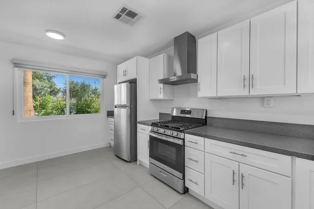 a kitchen with stainless steel appliances granite countertop white cabinets and a stove top oven