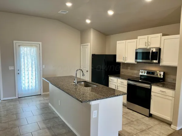 a kitchen with stainless steel appliances granite countertop a sink a stove a microwave a sink a refrigerator and grey cabinets