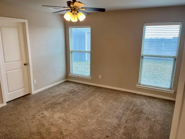 an empty room with windows and fan