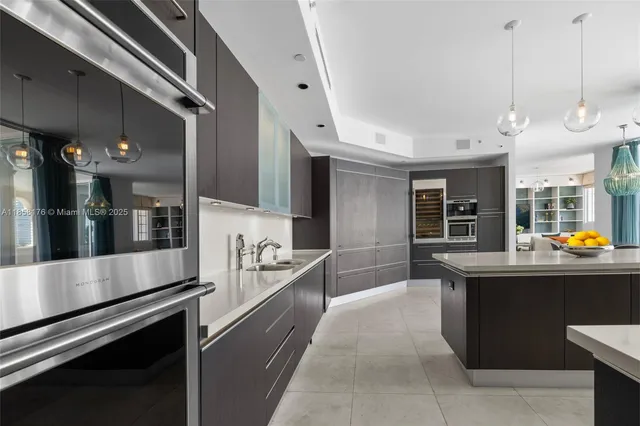 a large white kitchen with a large counter top space a sink stainless steel appliances and cabinets