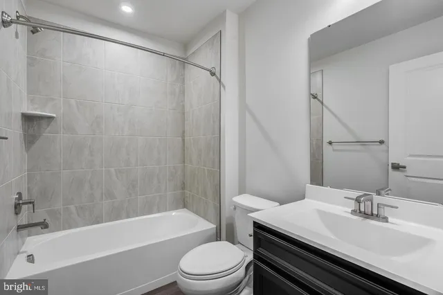 a bathroom with a bathtub shower sink vanity mirror and toilet