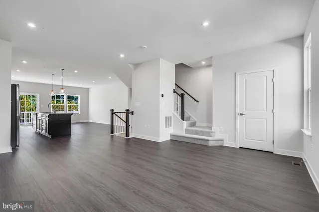 a view of a livingroom with wooden floor and a kitchen space with wooden floor