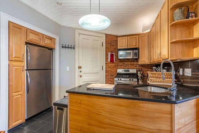 a kitchen with stainless steel appliances granite countertop a refrigerator a stove and a sink with granite countertops