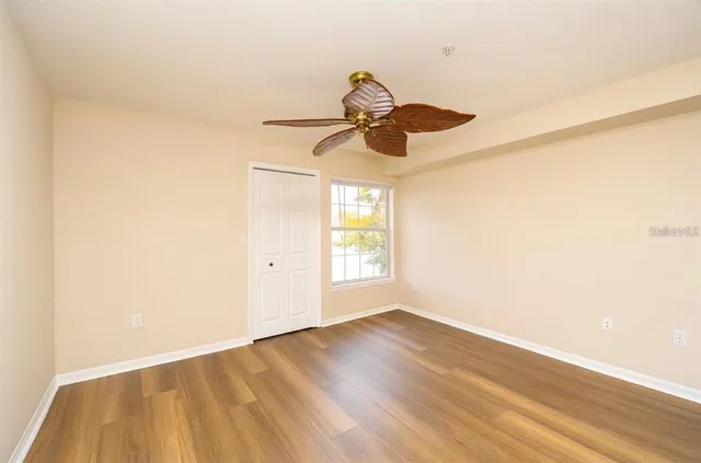 a view of an empty room with wooden floor and a window