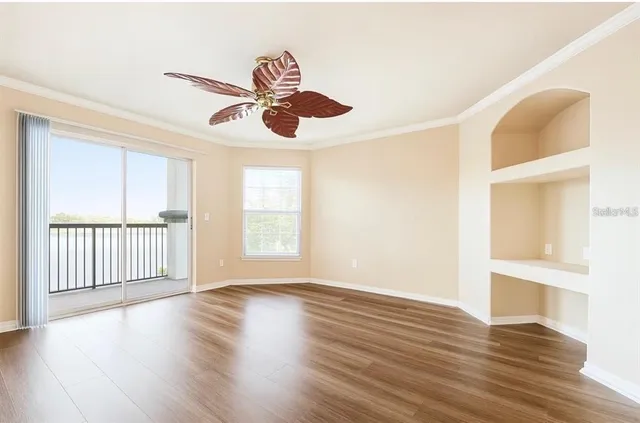 a view of an empty room with wooden floor and a window