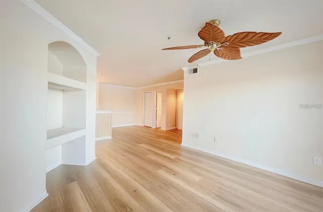a view of empty room with wooden floor and fan