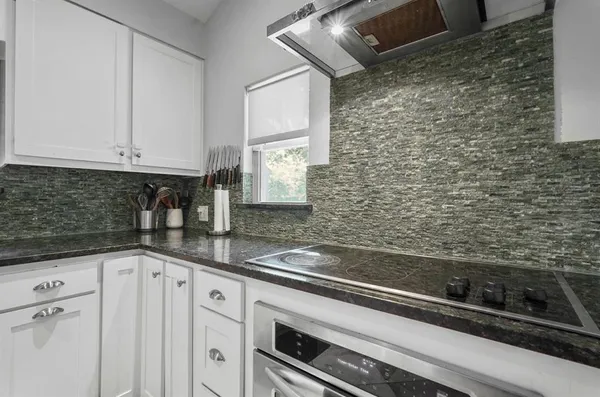 a kitchen with granite countertop white cabinets and stainless steel appliances