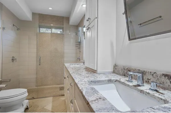 a bathroom with a granite countertop sink a toilet and shower