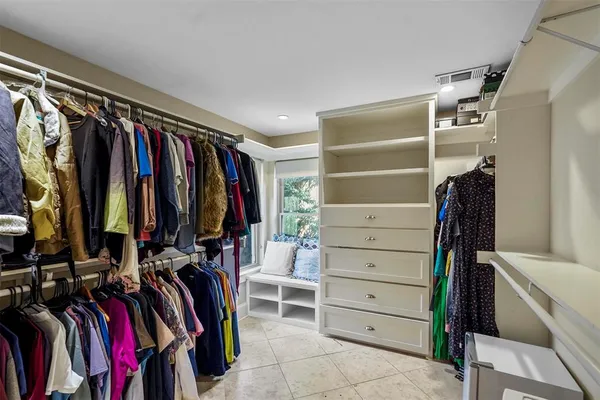 a view of walk in closet with clothes and shoes