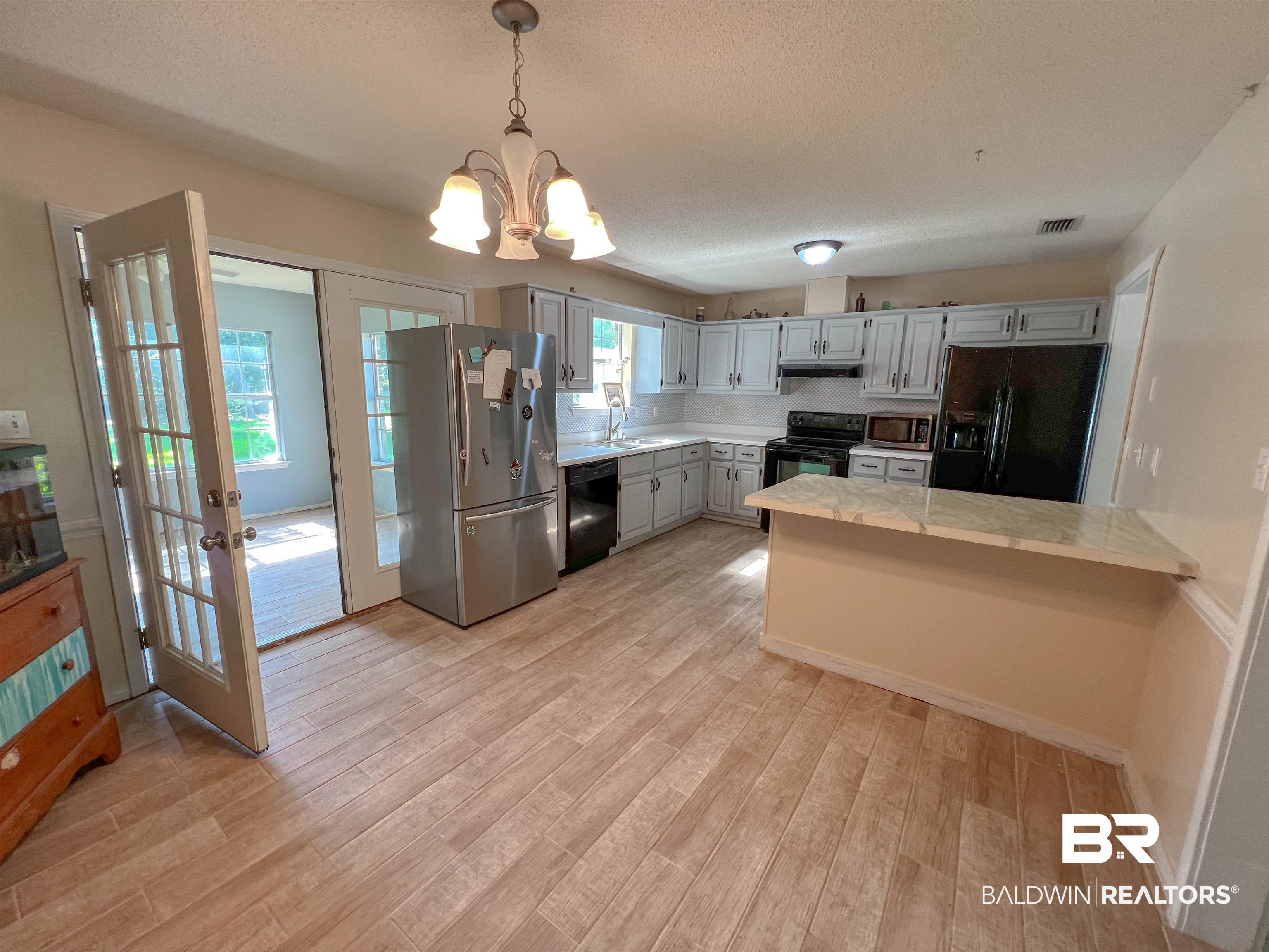 1200 South Juniper Street Foley, AL 36535 - Photo 3 of 23 Kitchen with black appliances, light hardwood / wood-style flooring, a notable chandelier, and a wealth of natural light