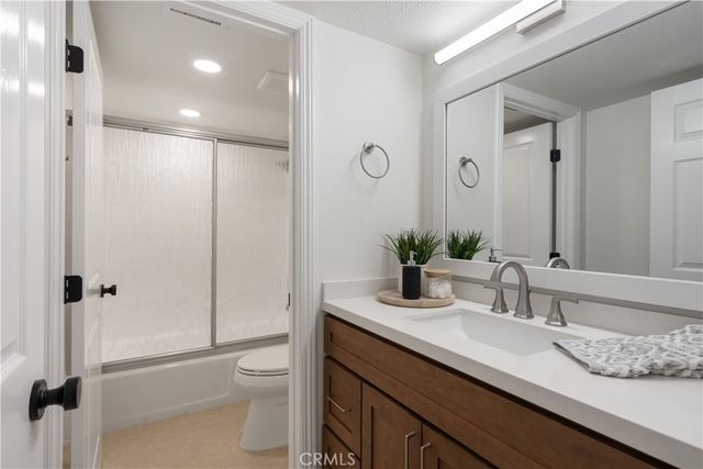 a bathroom with a granite countertop sink a toilet and shower