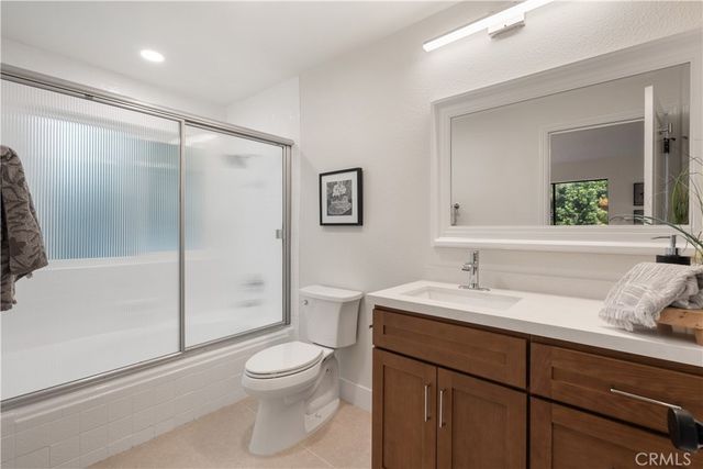 a bathroom with a granite countertop sink toilet a mirror and shower