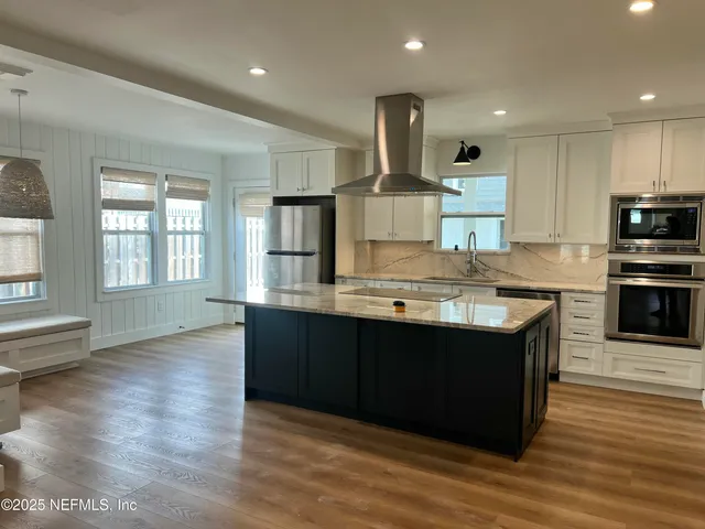 a kitchen with stainless steel appliances granite countertop a sink a stove and a wooden floors