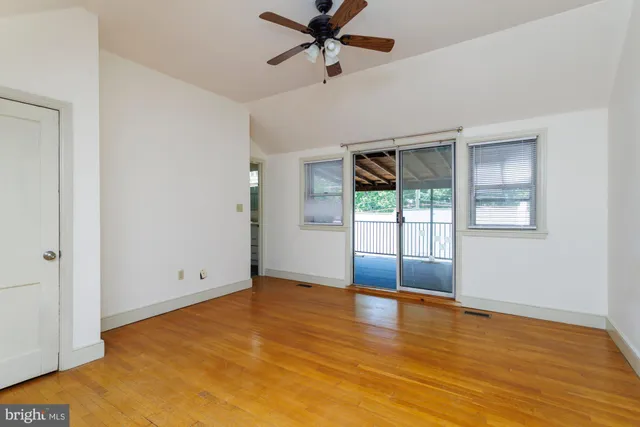 a view of an empty room with window and wooden floor