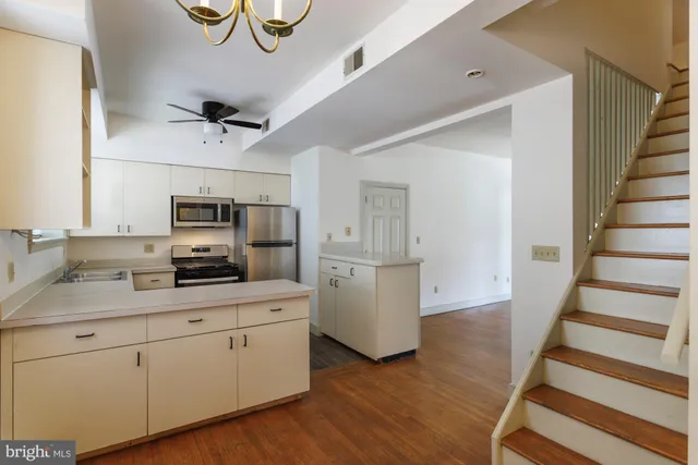 a kitchen with stainless steel appliances a sink cabinets and wooden floor