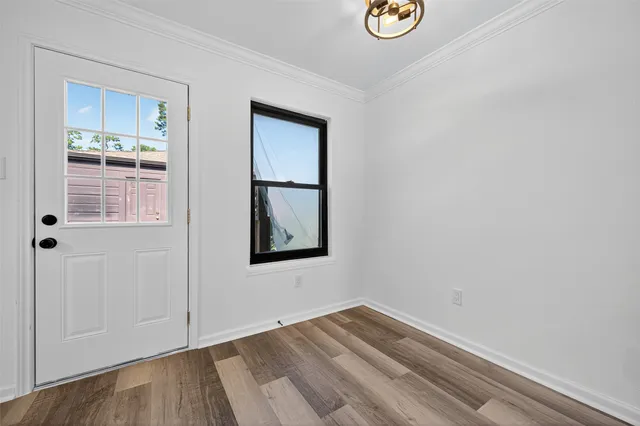 a view of an empty room with wooden floor and a window