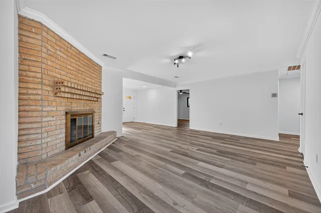 a view of empty room with wooden floor and fireplace