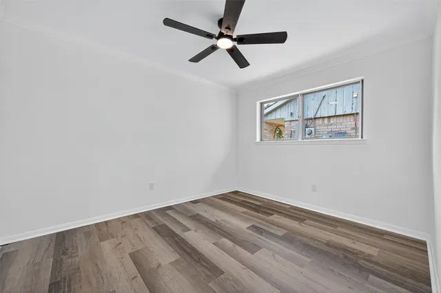 an empty room with wooden floor and ceiling fan