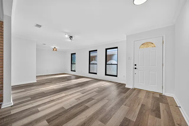 a view of empty room with wooden floor and window