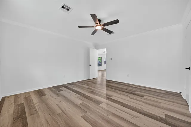 a view of empty room with wooden floor and ceiling fan