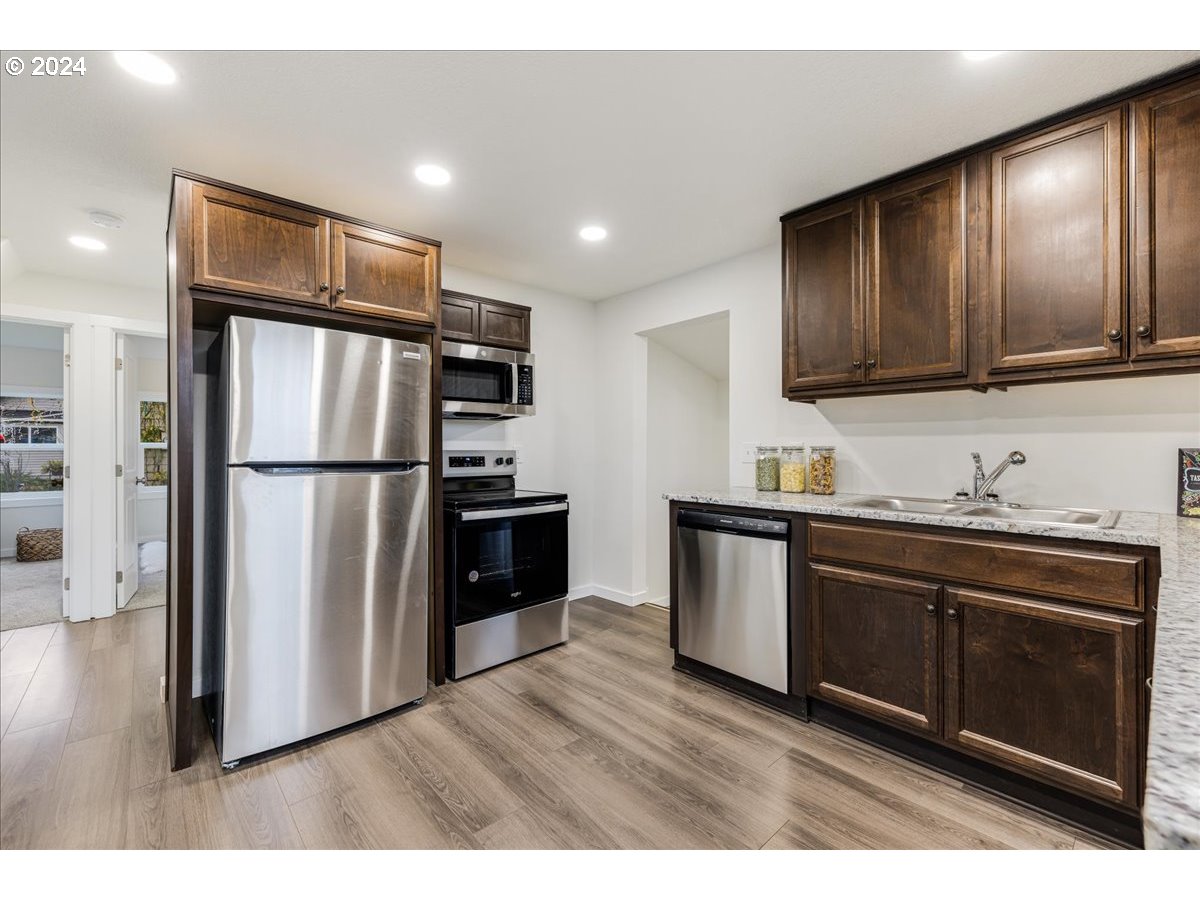 711 Southeast 5th Street Gresham, OR 97080 - Photo 20 of 44 a kitchen with granite countertop stainless steel appliances a refrigerator cabinets and wooden floor