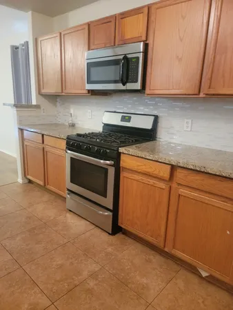 a kitchen with stainless steel appliances granite countertop a stove a sink and a microwave
