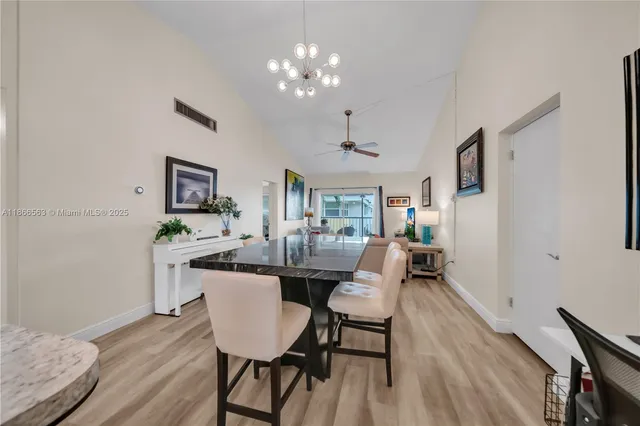 a dining room with wooden floor a chandelier a wooden table and chairs