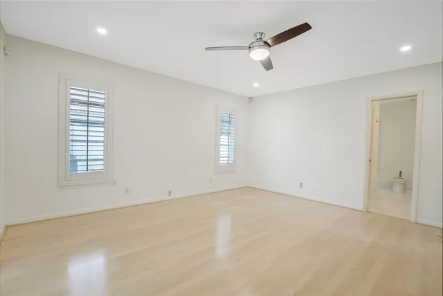 an empty room with windows and fan