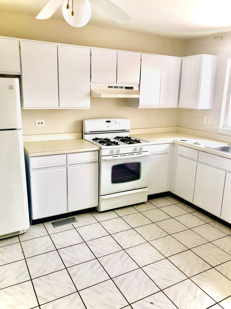 2017 Windemere Circle, Unit 2017 Schaumburg, IL 60169 - Photo 4 of 15 a kitchen with a sink a stove top oven and white cabinets